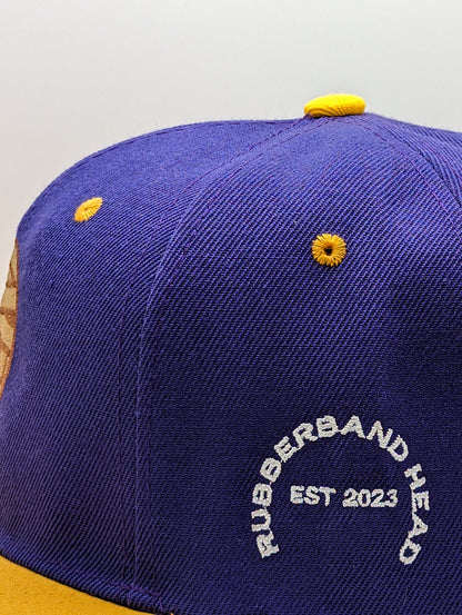 SNAPBACK CON CABEZA DE GOMA MORADO / DORADO