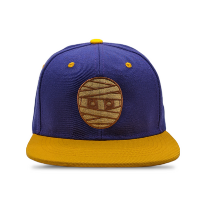 SNAPBACK CON CABEZA DE GOMA MORADO / DORADO