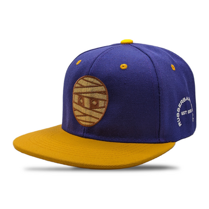 SNAPBACK CON CABEZA DE GOMA MORADO / DORADO